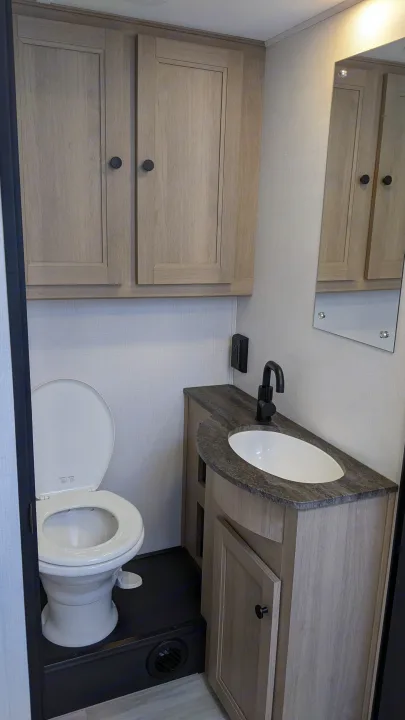 RV rental bathroom: compact toilet, sink vanity, and overhead storage. Modern design for comfortable travel.. Forest River Sunseeker 2025