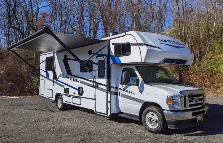 Explore with this Class C Sunseeker RV rental. White with blue/black graphics, awning extended. Ready for your camping adventure!. Forest River Sunseeker 2025