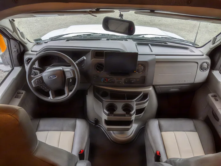 RV rental: Interior of a Ford E-Series van cockpit, featuring dashboard, steering wheel, central Sony screen, and front seats.. Forest River Sunseeker 2025