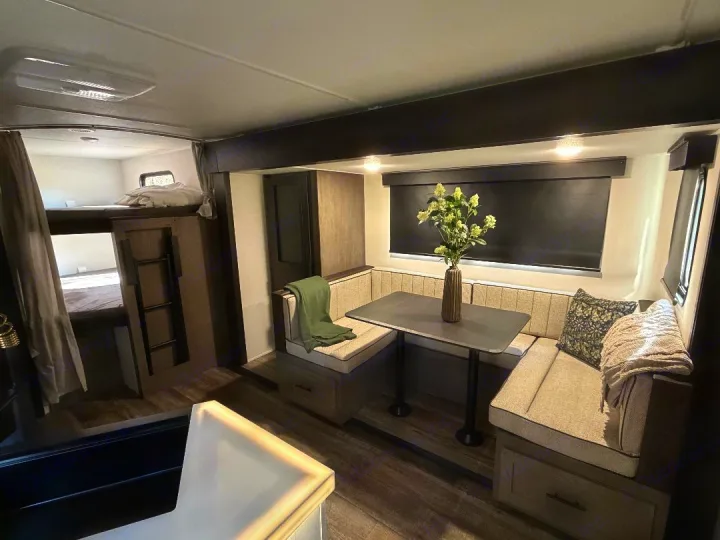 Modern RV rental interior featuring a dinette, full bunk beds, and comfortable seating.. Forest River Cherokee Alpha Wolf 2025