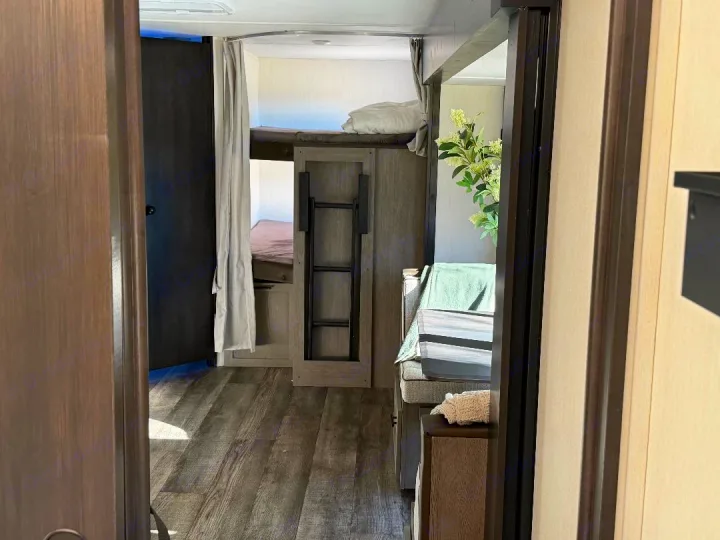 RV rental interior: Modern bunk beds, dinette, and living area visible in this compact camper space.. Forest River Cherokee Alpha Wolf 2025
