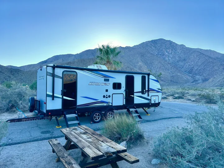 RV rental: A Cherokee Alpha Wolf travel trailer in a serene desert campsite, framed by majestic mountains and a picnic table.. Forest River Cherokee Alpha Wolf 2022