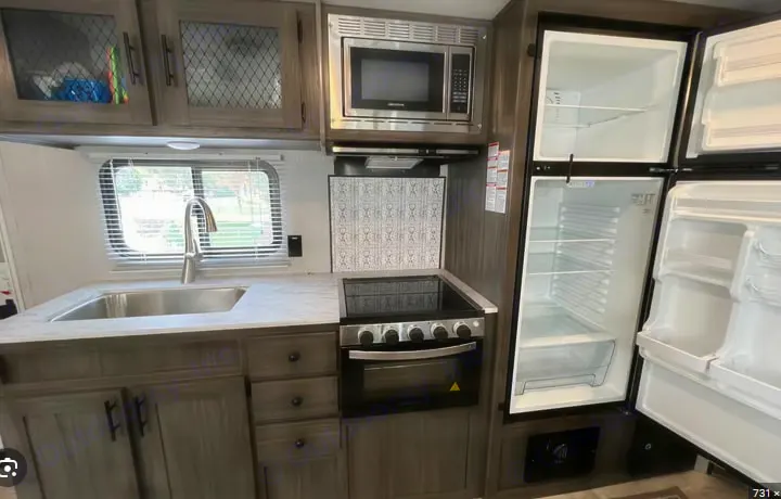 RV rental kitchen showing a modern interior with sink, microwave, stove, and an open refrigerator for convenient use.. Shasta Shasta 2020