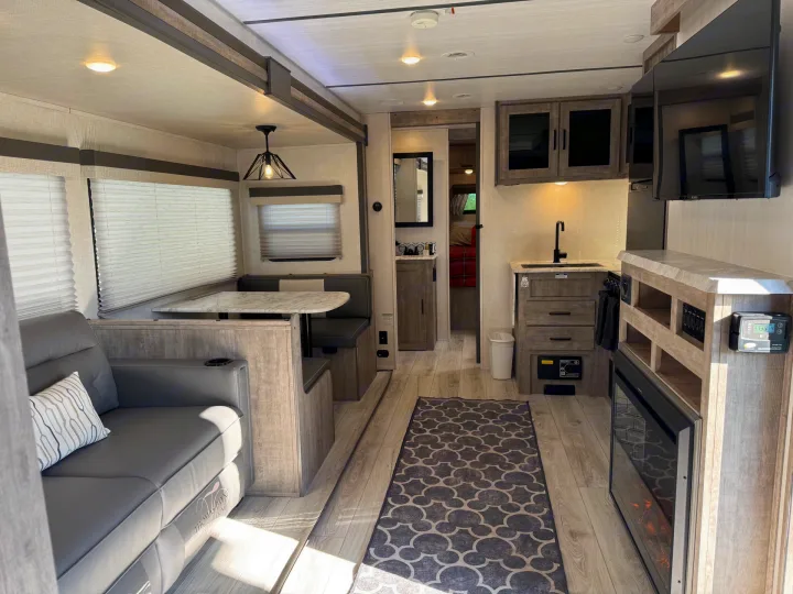 Spacious and modern RV rental interior, featuring living, dining, and kitchen areas, perfect for comfortable travel.. Forest River Surveyor 2023