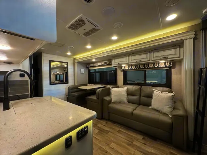 Experience comfort in this RV rental's modern interior: well-equipped kitchen, dinette, and spacious living area with sofa.. Entegra Coach Vision XL 2021