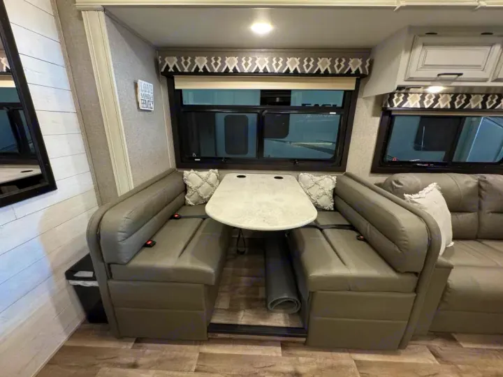 Inside an RV rental: a modern dinette with booth seating, table, and sofa, creating a comfortable living space.. Entegra Coach Vision XL 2021