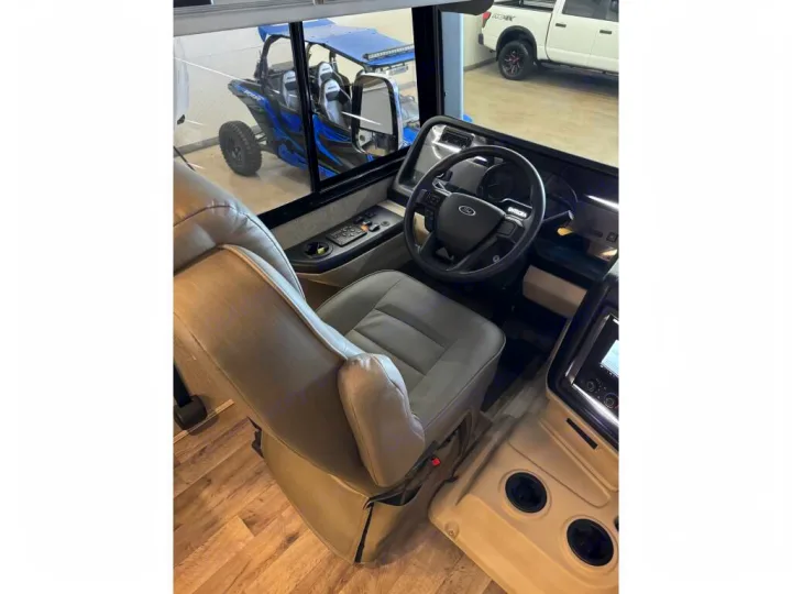Spacious RV rental driver's area, featuring a steering wheel, comfy seats, dashboard, and outside vehicle views.. Entegra Coach Vision XL 2021