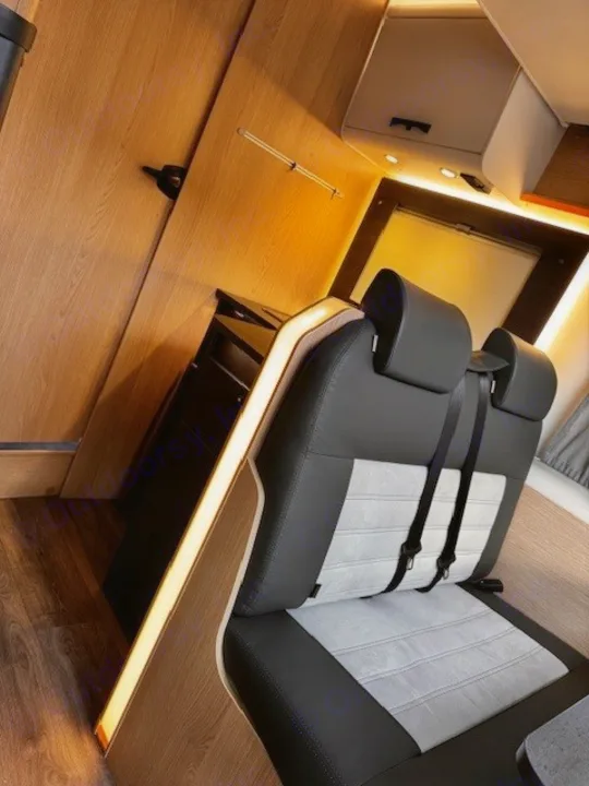 RV rental interior: Modern seating with headrests & seatbelts, warm wood walls, and ambient lighting for travel comfort.. Sunlight T690L 2025