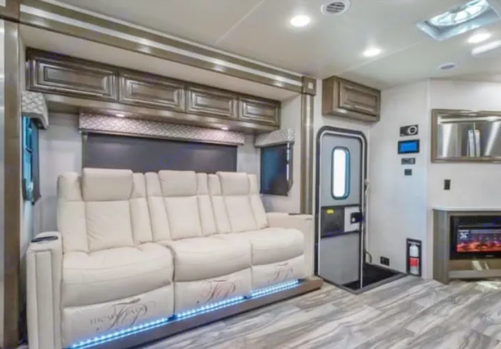 Plush rv rental interior: cream theater seating with LED lights, modern flooring, and fireplace for cozy travel.. Georgetown GT7 2022