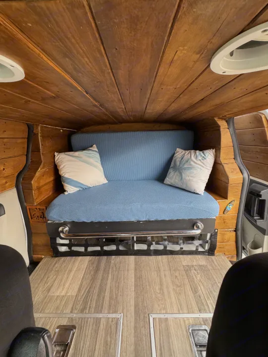 Step inside this cozy RV rental camper van with rustic wooden walls, a comfy blue sofa, and durable wood-look flooring.. Ram C/V Tradesman 2014