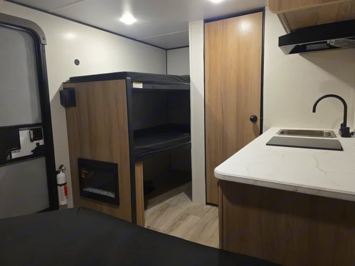 Inside this RV rental: kitchenette, bunk beds, and electric heater. Perfect for cozy adventures.. KEYSTONE COLEMAN 13B 2026