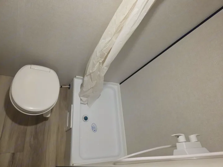 RV rental bathroom: overhead view of a compact toilet, shower, curtain, and soap dispenser.. KEYSTONE COLEMAN 13B 2026
