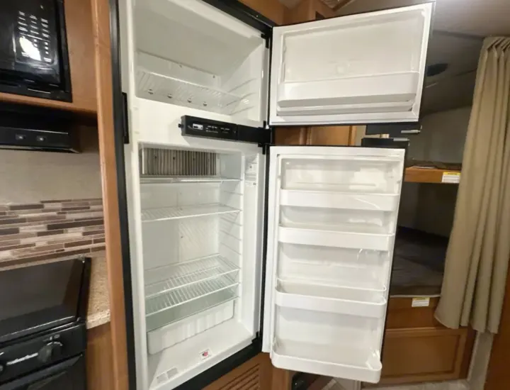 Clean, empty RV rental fridge/freezer, ready for your trip. Microwave, stove, and bunks nearby.. Crossroads RV Sunset Trail Super Lite 2017