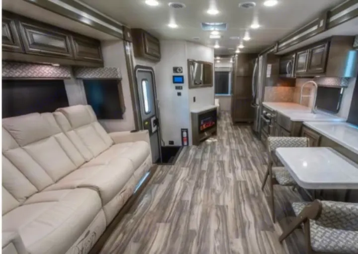 Spacious, modern RV rental interior featuring a comfy sofa, full kitchen, dining area, and fireplace for luxurious travel.. Georgetown GT7 2022
