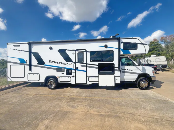 This white Sunseeker Class C rv rental, with bold blue and black graphics, is parked on concrete, ready for your next trip.. Forest River Sunseeker Classic 2025