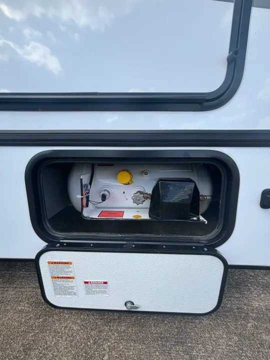 This RV rental's open propane compartment reveals the tank, regulator, and crucial safety warnings for safe gas usage.. Forest River Sunseeker Classic 2025