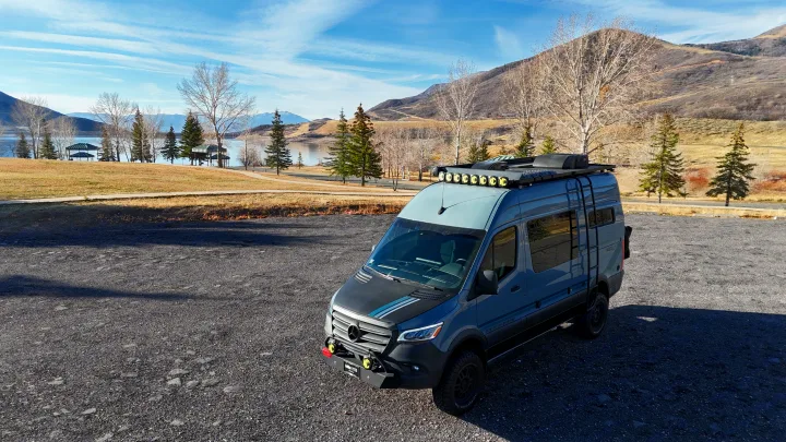 This adventure-ready Mercedes Sprinter van, ideal for your next RV rental, parked by a scenic lake and mountains.. Storyteller Overland Storyteller Overland Class B 2023
