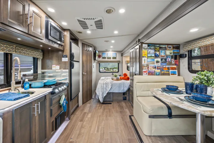 Inside a modern RV rental: complete kitchen, comfortable dining booth, and cozy sleeping area for your next adventure.. Dynamax Corp Isata 2021