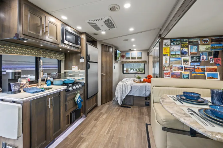This RV rental's compact interior features a well-equipped kitchen, cozy bed, and dinette area, perfect for comfortable travel.. Dynamax Corp Isata 2021