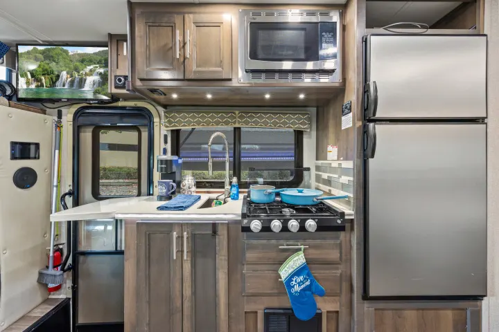 Step inside this RV rental, revealing a fully equipped kitchen with a microwave, fridge, stove, sink, and coffee maker.. Dynamax Corp Isata 2021