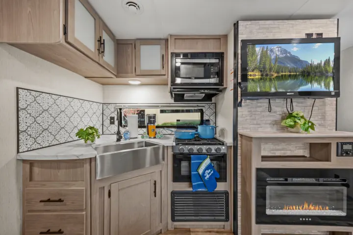 This cozy rv rental offers a well-appointed kitchen with stove, microwave, large sink, and an entertainment area with TV and fireplace.. Coleman Lantern 2022