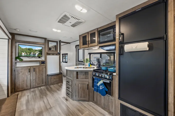 Modern RV rental interior with a fully equipped kitchen (stove, fridge, microwave) and cozy living area with TV.. Heartland RVs Pioneer 2021