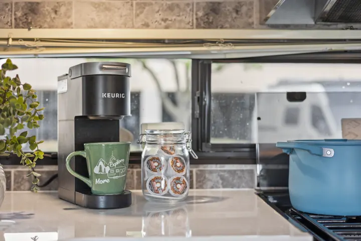 Compact kitchen in an RV rental, featuring a Keurig coffee maker, mug, and coffee pods. Ready for your adventure.. Forest River EVO CSJT2990 2022