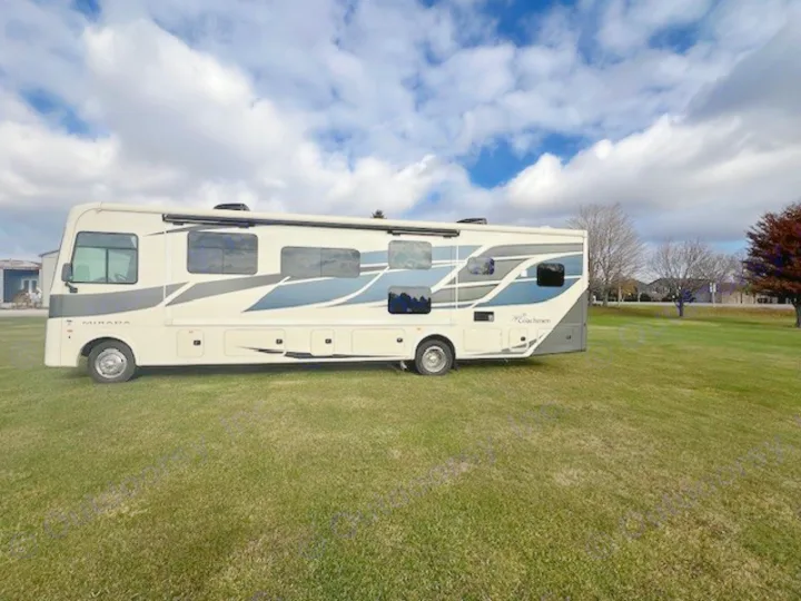 Cream-colored Coachmen Mirada RV rental on green grass under a partly cloudy sky, ready for your next adventure.. Forest River Coachmen Mirada 2022