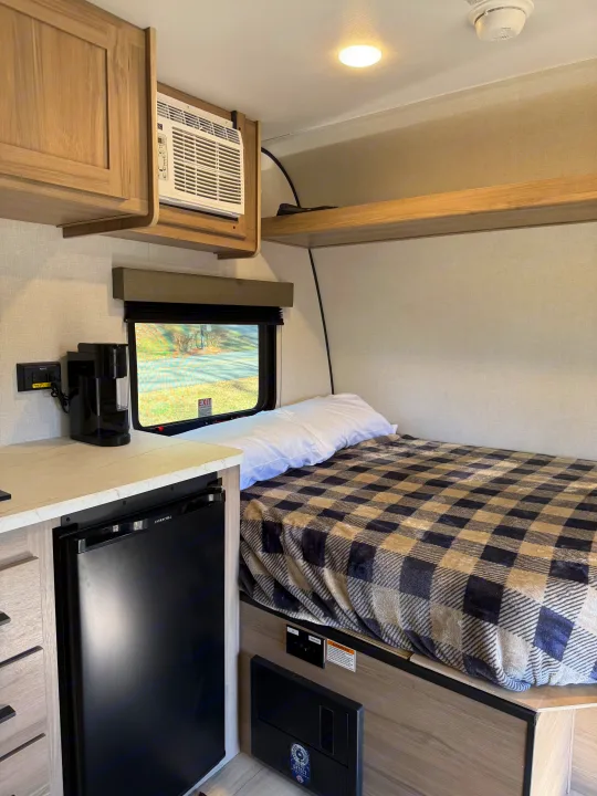 Cozy rv rental interior with bed, AC, mini-fridge, and coffee maker, perfect for road trips.. Keystone Coleman 13R 2026