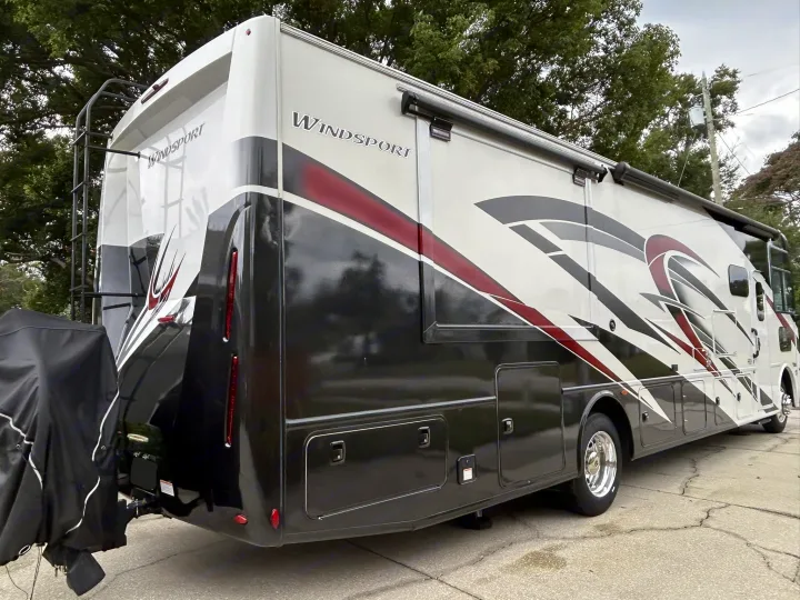 A large Thor Windsport RV rental, white, black, and red graphics, parked and ready for your next road trip adventure. Features awning & ladder.. Thor Windsport 2023