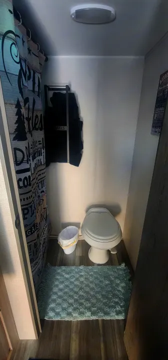Compact RV rental bathroom features a toilet, shower curtain, and towel storage, maximizing a small, functional space.. Heartland Pioneer 2025