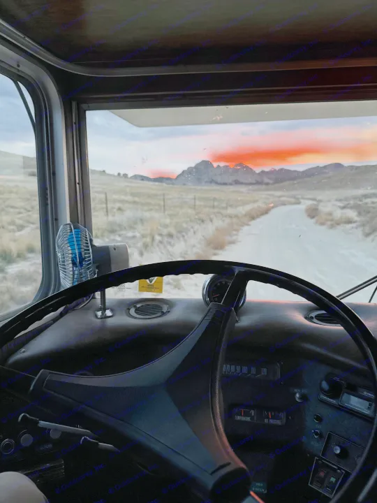 RV rental adventure: Scenic desert sunset from the cockpit, driving a dirt road towards rugged mountains.. International 510A 1973