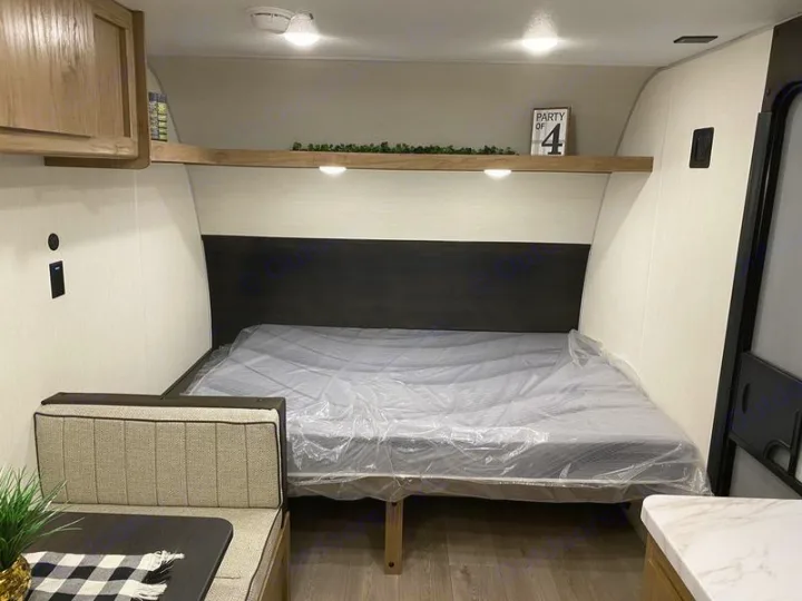 This RV rental interior shows a compact living space with a bed, dinette, and overhead storage.. Forest River Cherokee Wolf Pup 2025