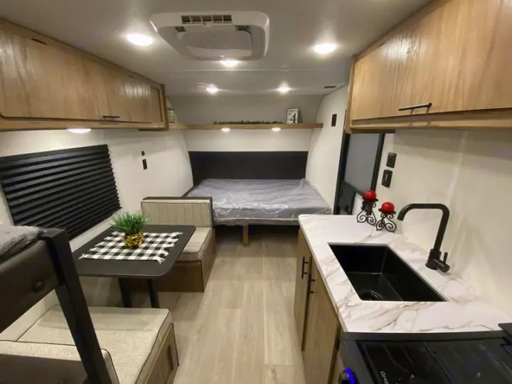 This modern **rv rental** interior showcases a compact kitchen, dinette area, and comfortable bed, ideal for travel adventures.. Forest River Cherokee Wolf Pup 2025