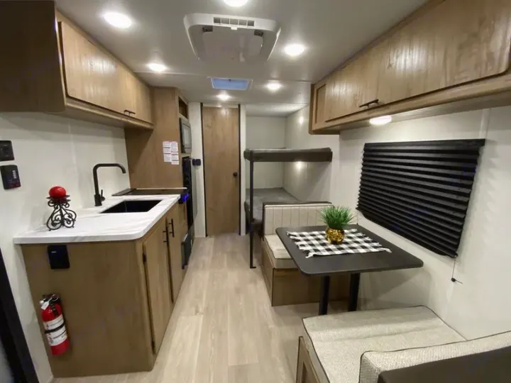 Inside this RV rental: A kitchen with sink, dining area with table/benches, and bunk beds for a cozy, functional space.. Forest River Cherokee Wolf Pup 2025
