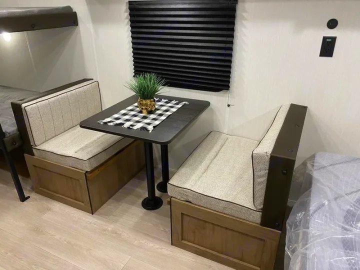 Cozy RV rental dinette with light-colored benches, a dark table, and bunk beds. Modern interior for travel.. Forest River Cherokee Wolf Pup 2025