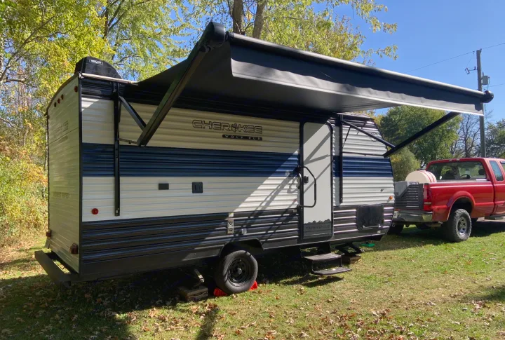 This Cherokee Wolf Pup rv rental travel trailer features an extended awning, parked in a sunny outdoor setting with a red truck.. Forest River Cherokee Wolf Pup 2025