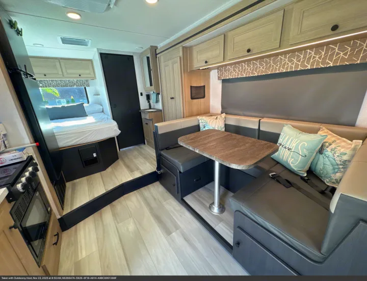 Cozy rv rental interior features a modern dinette with table & cushions, a comfy bed, and light wood accents.. Forest River Sunseeker 2026