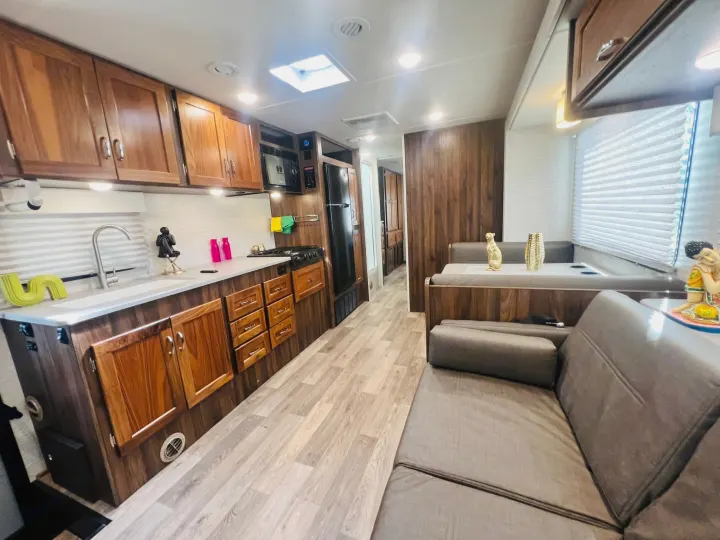 Spacious RV rental interior with full kitchen, dinette, and sofa. Modern wood cabinets & light flooring.. Winnebago Outlook 2020
