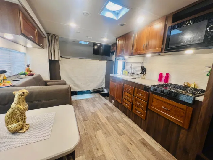 Modern RV rental interior: a well-equipped kitchen, cozy living space, and wood flooring for comfortable travel.. Winnebago Outlook 2020