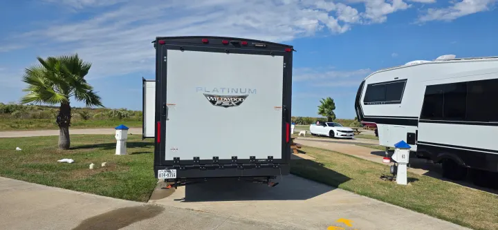 An RV rental site showcases a Wildwood travel trailer, a Brinkley fifth-wheel, and a white convertible on a sunny day.. Forest River Wildwood FSX Platinum 2024