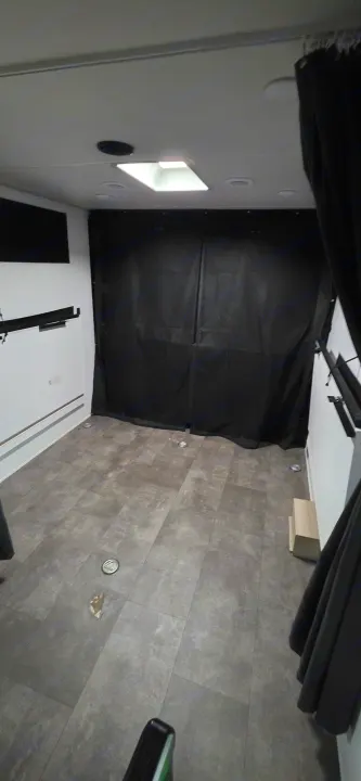 Spacious RV rental interior featuring gray tiled floor, white walls, black curtains, overhead lighting, and floor tie-downs.. Forest River Wildwood FSX Platinum 2024