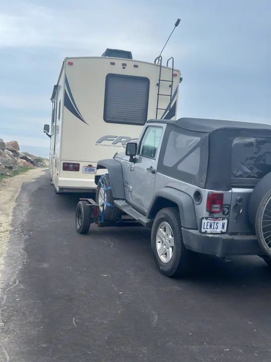 An RV rental tows a Jeep on a dolly, perfect for vacation travel and road trips, offering flexible exploration.. Acme Tow Dolly Company Two Wheel Dolly 2016
