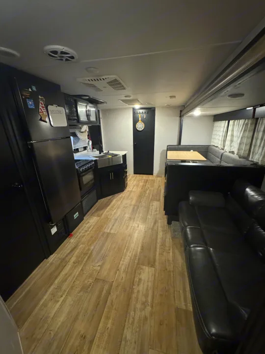 This modern travel trailer rv rental interior features a kitchen, dinette, and sofa. Enjoy compact, functional living.. Forest River Cherokee Grey Wolf 2022