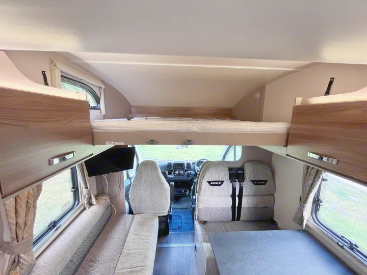 Explore this RV rental's cozy interior, featuring a living area, over-cab bunk, and bright front cabin.. Swift Edge 486 2024