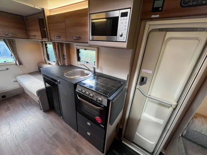 This RV rental features a modern kitchen with an overhead microwave, integrated sink, stove, and oven, plus comfortable bench seating.. Swift Edge 486 2024
