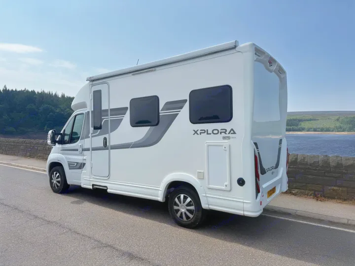 White Xplora campervan RV rental on a scenic road overlooking a lake, perfect for your next outdoor adventure.. Moto-Trek Xplora FDB 2025
