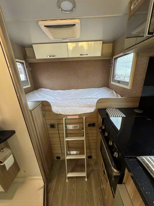 Cozy rv rental interior featuring a bunk bed with ladder, overhead cabinets, and a compact kitchen. Ideal for road trips.. Moto-Trek Xplora FDB 2025