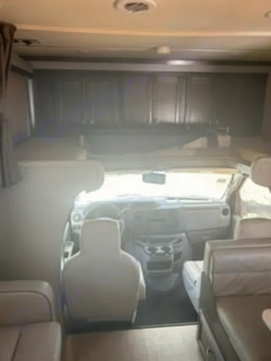 RV rental interior: View from the cabin towards the front cockpit, featuring the steering wheel, dashboard, and overhead bunk.. Gulf Stream Conquest 2022