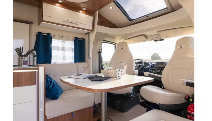 Spacious, modern RV rental interior with a light-filled dining area, kitchen counter, and swivel front seats, ideal for travel.. PILOTE P726 C 2026